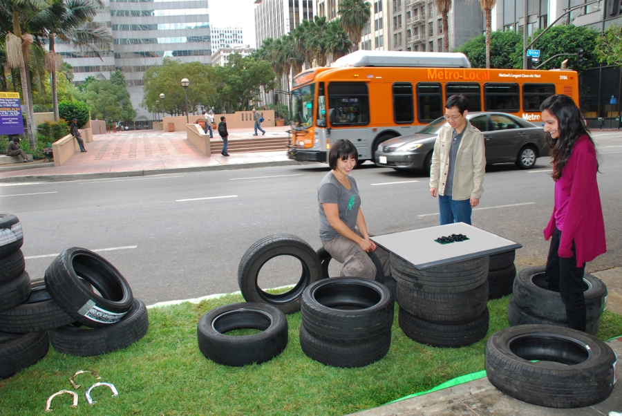 group arranges tires to form seating on turf surface in parking space